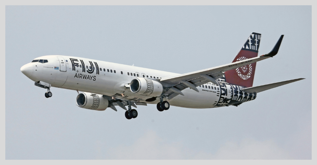 A large Fiji Airways jetliner flying in a clear blue sky, promoting the cheapest flights from the US to New Zealand.
